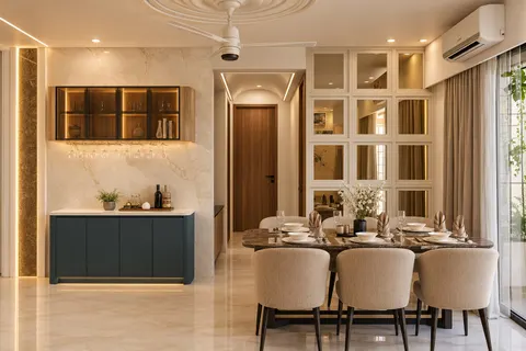 Dining, Gulmohar House. A six-seat table under a ceiling medallion, a mirrored cabinet wall, and a lit bar niche set in marble.